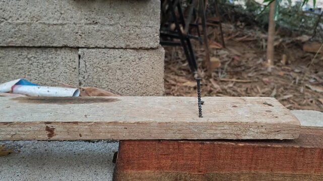 Detail shot of a sledgehammer driving a heavy screw fastener into timber planks