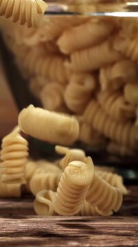 Fusili pasta falls on a wooden table. Filmed on a high-speed camera at 1000 fps. High quality FullHD footage