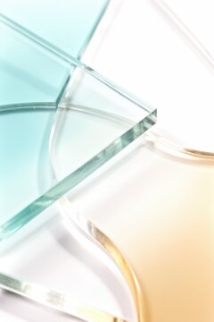 Glass panels overlapping in soft teal and amber tones on white background