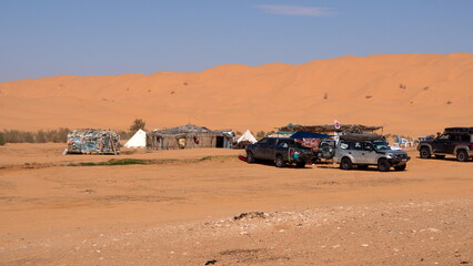 Four wheel drive vehicles parked around buildings at an oasis with tourist facilities in the Sahara Desert outside of Douz, Tunisia © Angela