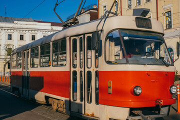 Fototapeta premium Kyiv, Ukraine - May 5, 2026: Red retro tram on Kontractova square - Podil district. Red tram is popular touristic transport and attraction. Against of the residential complex Podol Prestige.