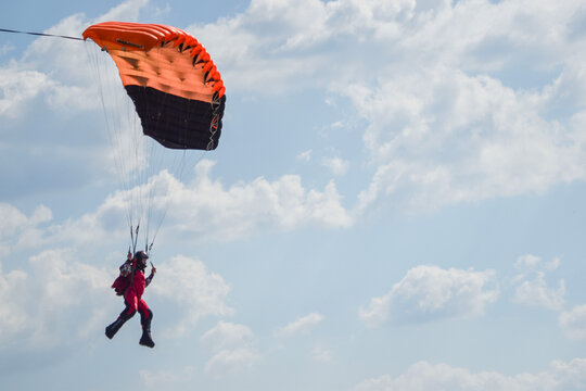 Paraglider descending under bright green canopy against dramatic sky