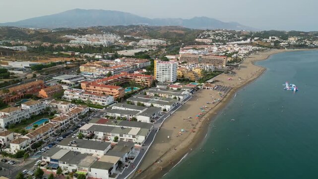 High angle view of Benalmadena coastline near Malaga, Spain. Scenic resort beach with blue sea waves, golden sand, beachfront luxury hotels, and holiday villas on the Costa del Sol.