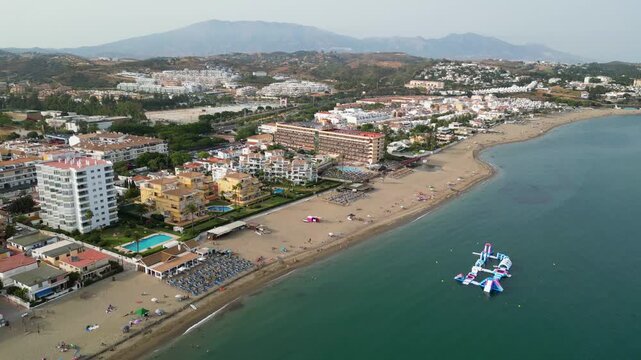 High angle view of Benalmadena coastline near Malaga, Spain. Scenic resort beach with blue sea waves, golden sand, beachfront luxury hotels, and holiday villas on the Costa del Sol.