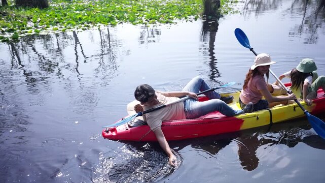Happy Asian family parents and young daughter kayaking together in lake. Father, mother and child enjoy adventure travel nature active lifestyle paddling canoe during outdoor summer holiday vacation.