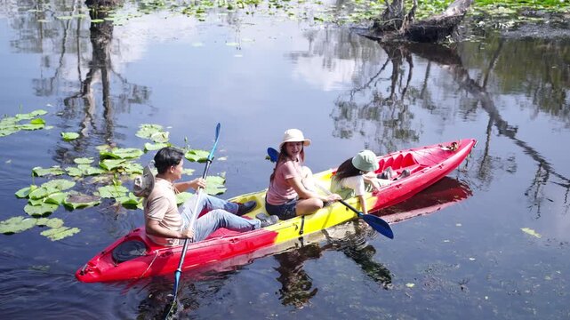 Happy Asian family parents and young daughter kayaking together in lake. Father, mother and child enjoy adventure travel nature active lifestyle paddling canoe during outdoor summer holiday vacation.