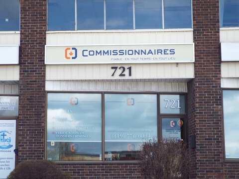 Gatineau, Quebec, Canada &ndash; April 21, 2026: A storefront for "COMMISSIONNAIRES" features frosted window signage listing security and background check services at 721 Boulevard Saint-Joseph.