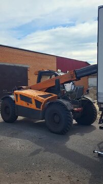 Telescopic handler works alongside a cargo truck for loading operations, supply chain efficiency, industrial transport hub. joint operations, logistics coordination, freight loading.