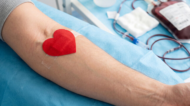 Blood donation process with a red heart on the arm, medical equipment in the background for healthcare and charity concept