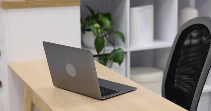 Laptop on wooden desk and chair in office. Camera moving
