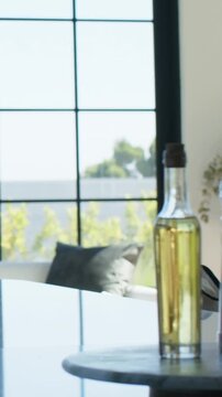 Vertical video: Panning lens moving three bottles off round table showing grid window, dark pillow