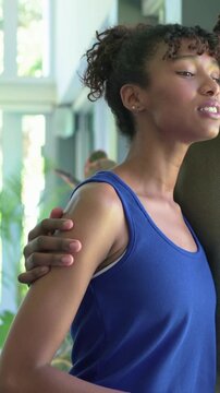 Vertical video: Talking woman in blue tank, man in olive tee holding, showing windows, sofa at home