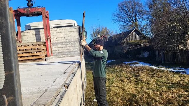 Worker handling aerated concrete blocks on a transport vehicle, industrial building logistics, material supply