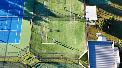 Obraz premium Aerial View of Tennis Players on a Green Court With Long Shadows
