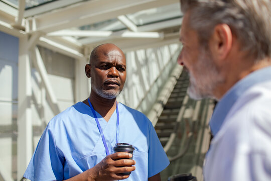 Healthcare workers talking during coffee break in hospital corridor