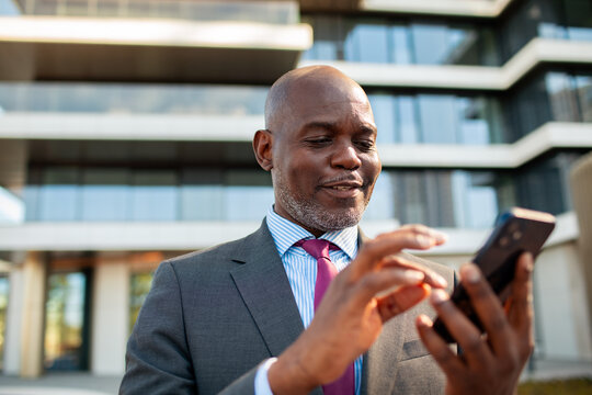 Business executive using smartphone outside modern office building