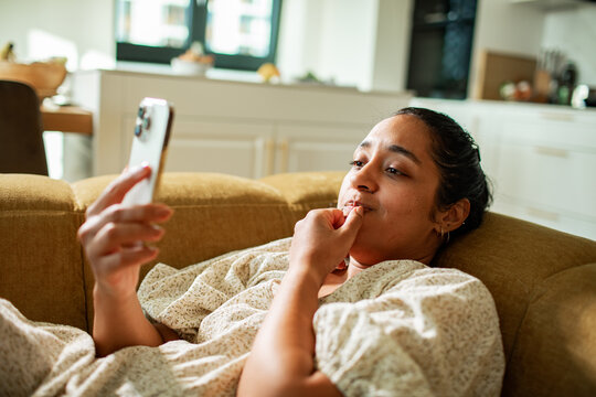Young woman using smartphone on sofa at home