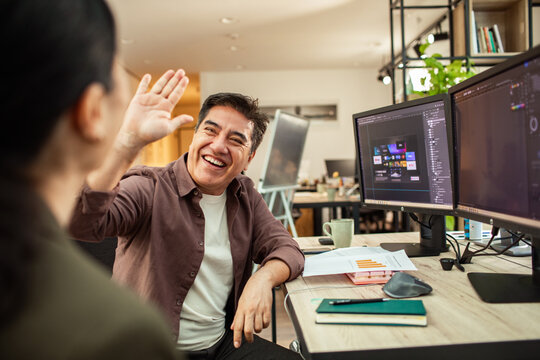 Smiling designer giving coworker high five in modern office