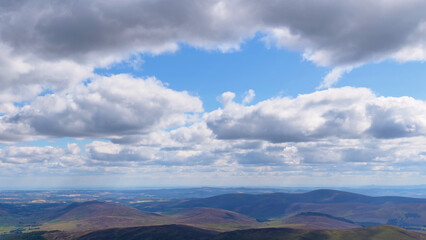 Fototapeta premium Aerial View of Rolling Scottish Highland Hills Under Dramatic Cloudscape