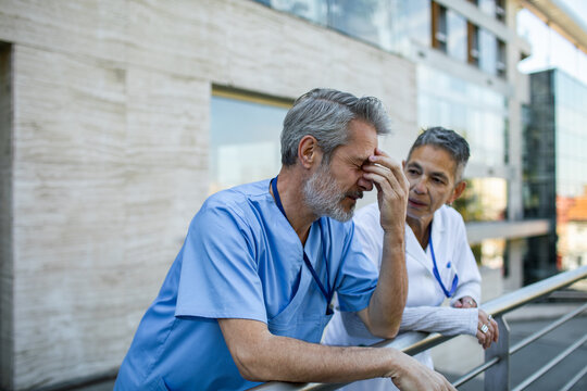 Stressed healthcare workers consoling outside hospital building