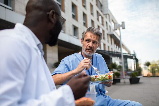 Doctors eating salad on lunch break outside hospital