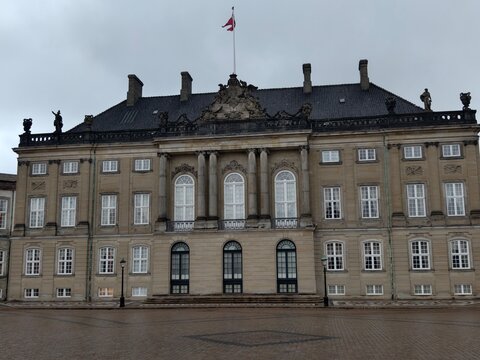 Copenhagen,Denmark-Nov.24th 2025: Front medium shot of the Amalienborg Palace exterior in Copenhagen, featuring the flying Danish flag on top.