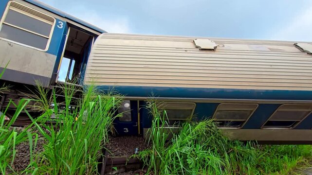 Ground level view of a major passenger train derailment, showing an overturned railway carriage beside the tracks and severe rail infrastructure damage at the accident scene.