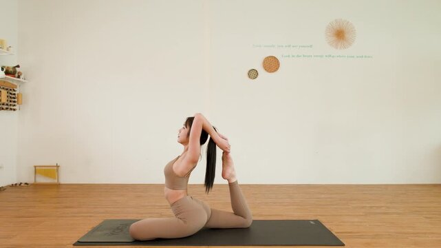 Asian Woman Practicing One Legged King Pigeon Yoga Pose in Studio