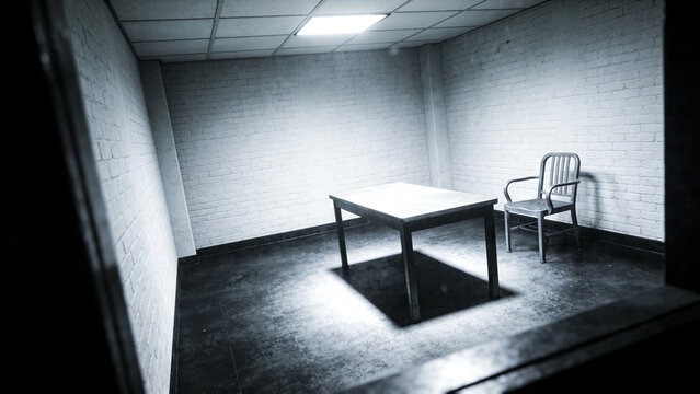 A dimly lit interrogation room with a table and chair inside.