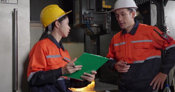Technicians reviewing machine setup with clipboard in auto parts factory