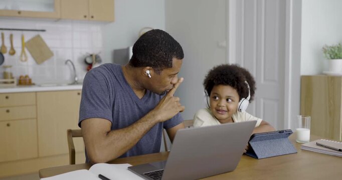 Smile father young toddler son wearing headphones using laptop together online learning and family bonding at home. Freelance work remote single dad lifestyle