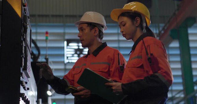 Technicians reviewing machine setup with clipboard in auto parts factory