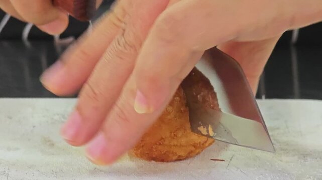 Cutting a crispy deep-fried boiled egg with a knife.