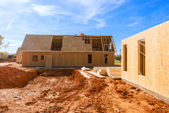 Workers on building new homes with wooden beams frames trusses framing materials in rural site.