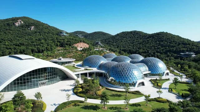 Modern geodesic dome complex with lush green surroundings and clear blue sky.