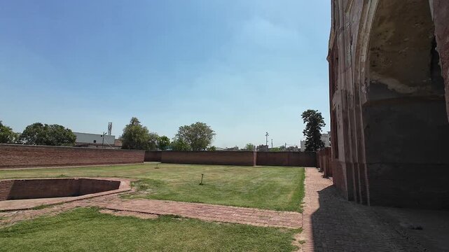 Historic Architectural Features of the Mughal Era Kabuli Bagh Mosque Displaying Both Exterior Brick Arches and Detailed Interior Plaster Carvings