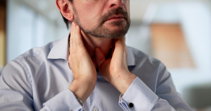 Older Man Sitting At Table, Touching Neck Due