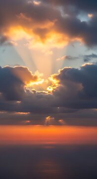 Stunning golden sunset rays breaking through dramatic storm clouds over the ocean.