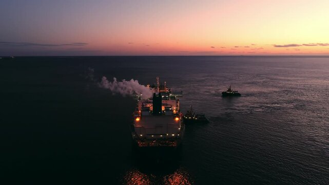 A large LNG tanker docks at an industrial port terminal for cargo operations at dusk