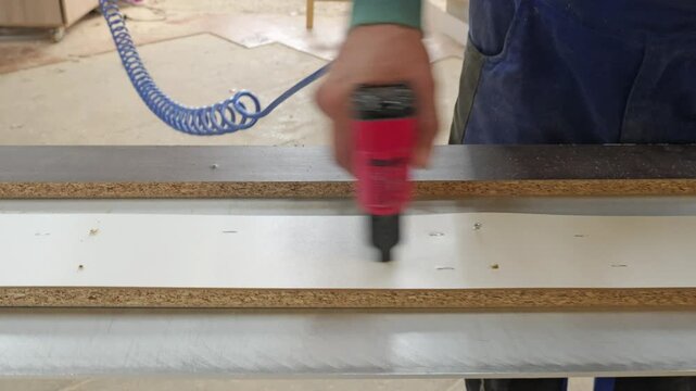Carpenter assembling furniture with a pneumatic nail gun