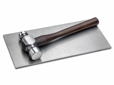 Compact ball peen hammer with a polished steel head and dark wooden handle resting on a simple brushed metal plate metalworking craft and workshop tool concept isolated on pure white