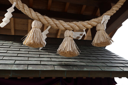 Japanese shimenawa straw rope with shide paper at a shrine.