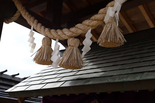 Japanese shimenawa straw rope with shide paper at a shrine.