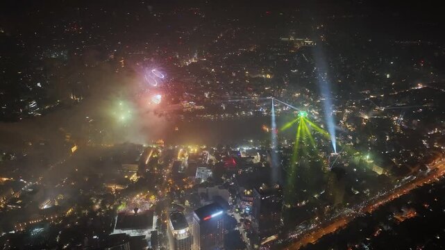 High angle drone view of fireworks and laser lights surrounding Hoan Kiem Lake in central Hanoi during festive nighttime celebration.
