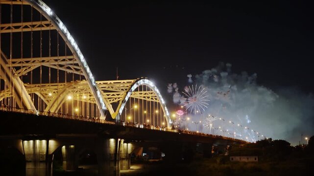 Fireworks exploding beside illuminated Dong Tru Bridge near Vietnam National Exhibition Center during vibrant nighttime celebration in Hanoi.