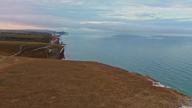 Aerial view of Seven Sisters Cliffs with white chalk faces and grassy clifftops overlooking the sea Exceat, England, United Kingdom.