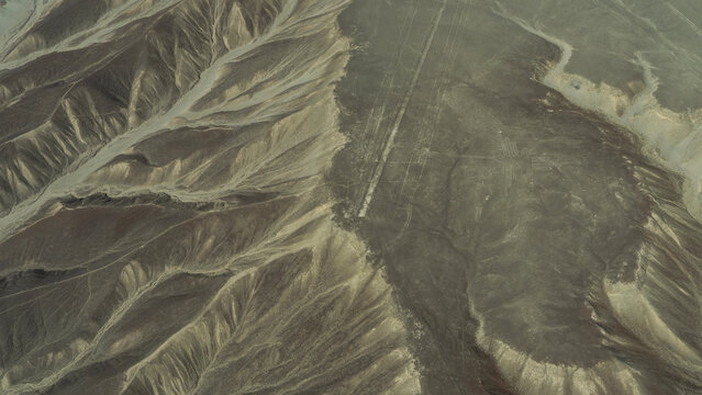 Desert, aerial view of the Nazca lines. There is a giant hummingbird geoglyph on a sandy plateau. Peru.