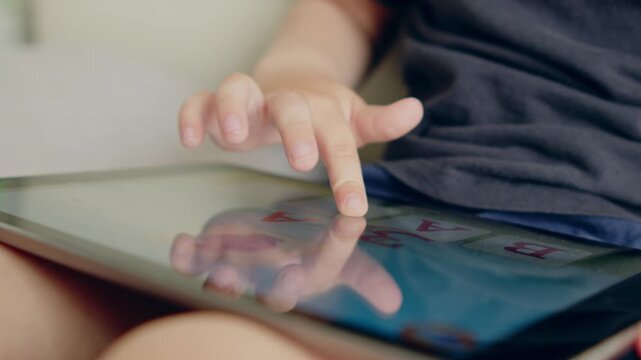 Close-up of a child's hands learning on an ipad.