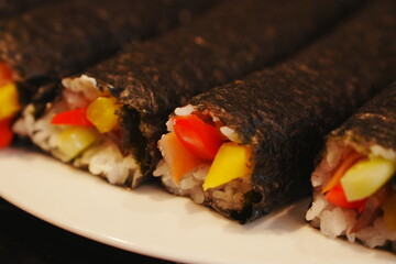 Colorful Maki Sushi Rolls with Red Pepper Yellow Pepper and Cucumber on White Plate Shallow Depth of Field © lumerb