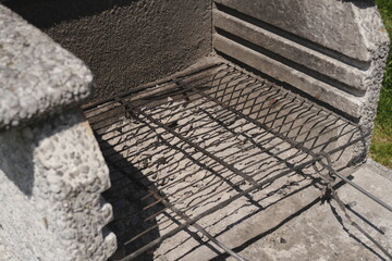 Fototapeta premium Empty Weathered Metal Grill Grate in Rustic Outdoor Concrete Barbecue Pit for Summer Cooking Preparation and Backyard Gatherings